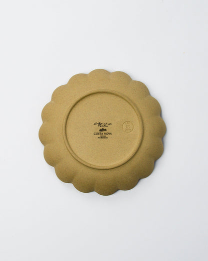 Underside of the brown scalloped stoneware plate on a white background