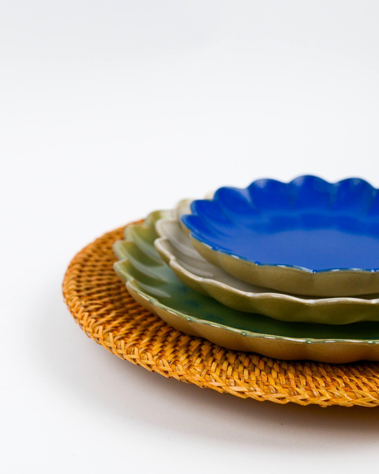 Stack of ceramic plates with scalloped edges on a woven placemat