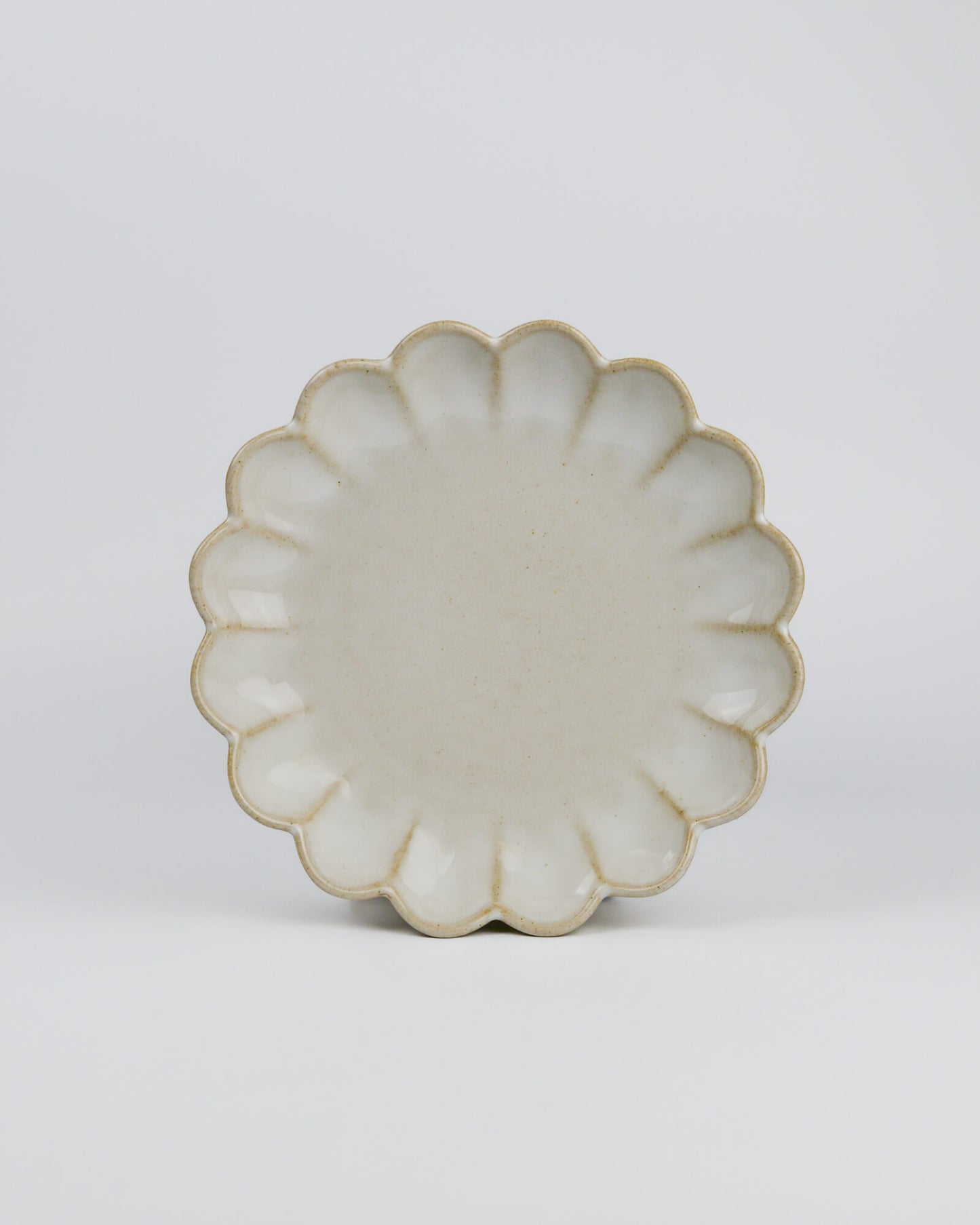 Decorative ceramic plate with a scalloped edge on a white background