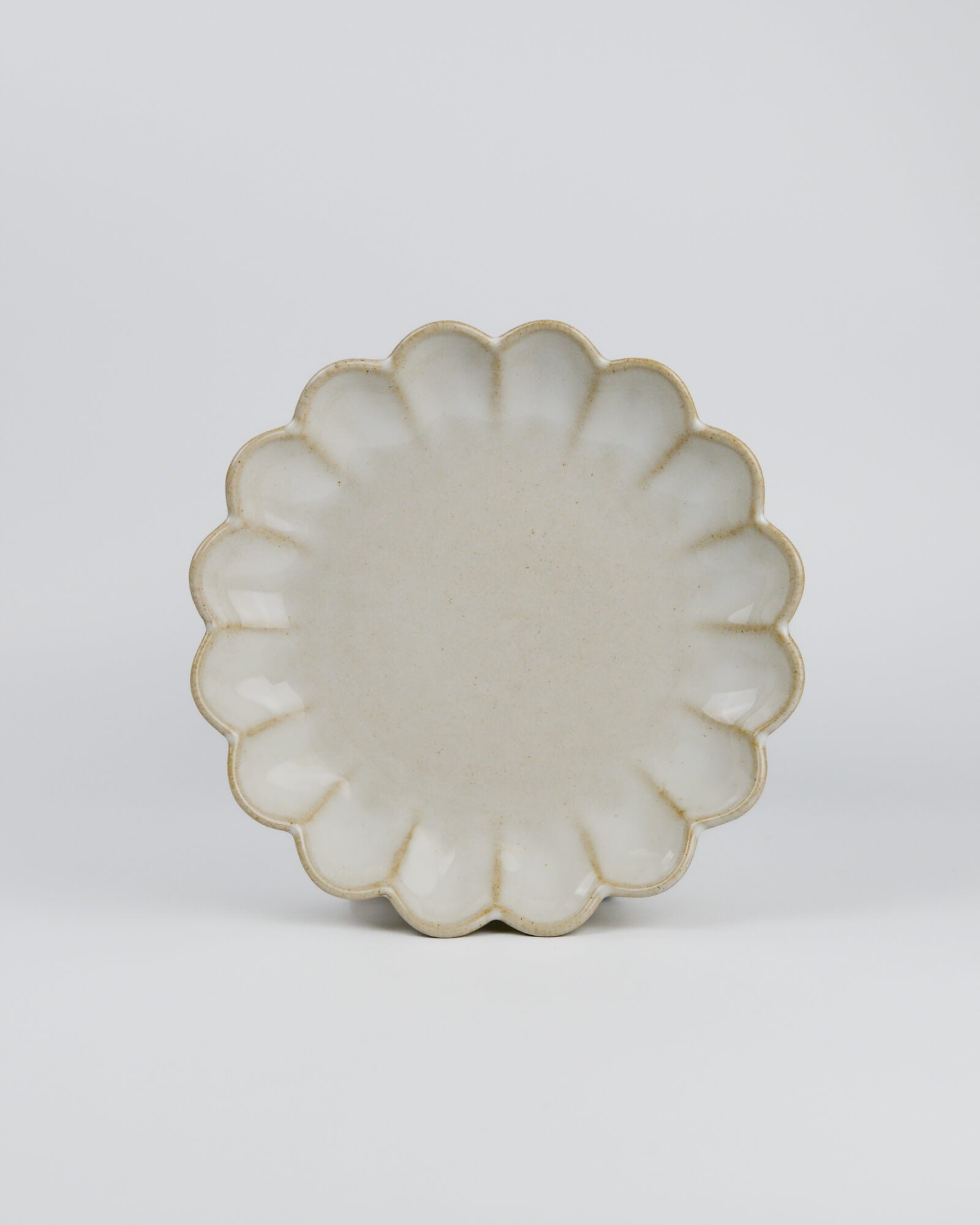 Decorative ceramic plate with a scalloped edge on a white background