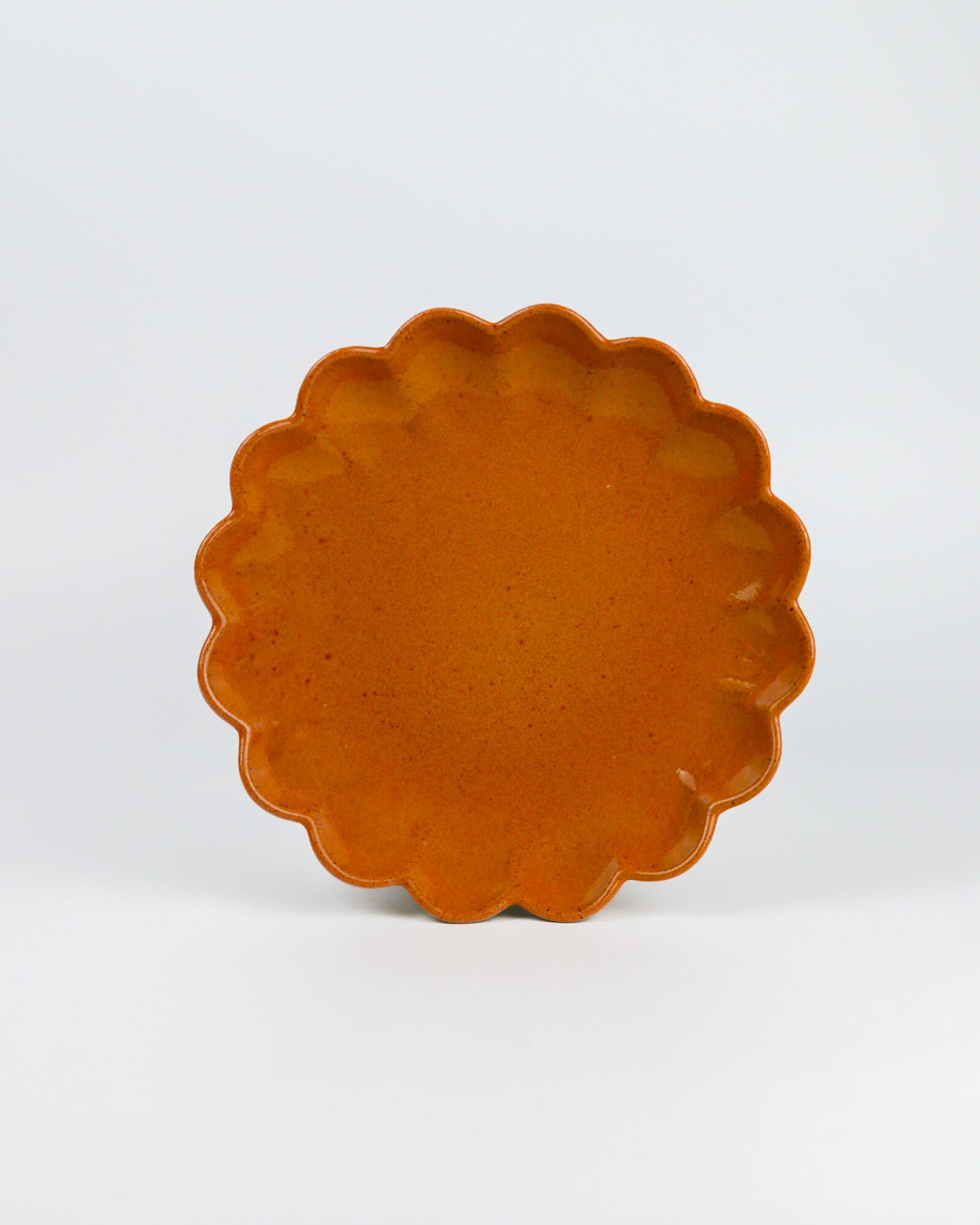Tumeric scalloped edge ceramic appetiser plate on a white background