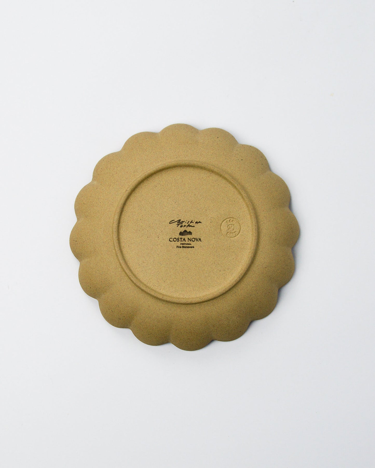 Underside of a stoneware scalloped plate on a white background