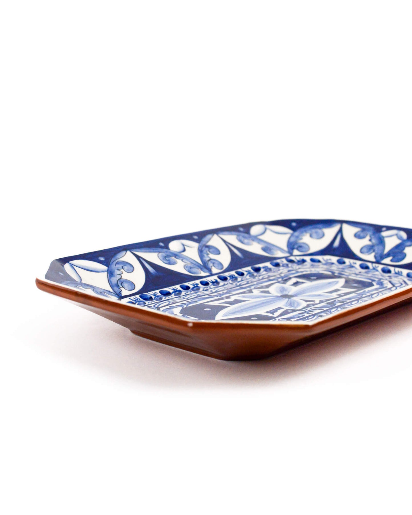 Decorative ceramic terracotta plate with blue and white pattern on a white background