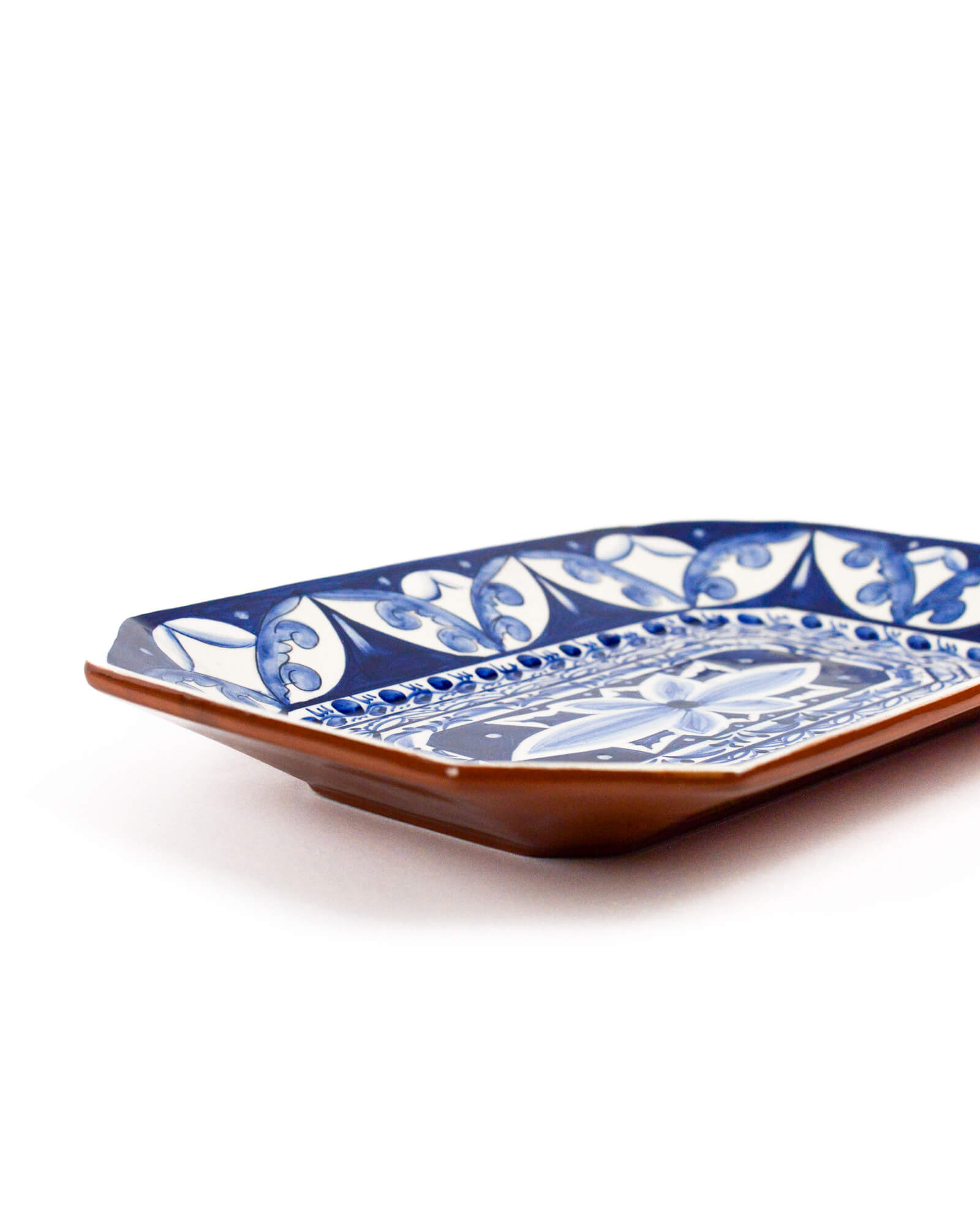 Decorative ceramic terracotta plate with blue and white pattern on a white background