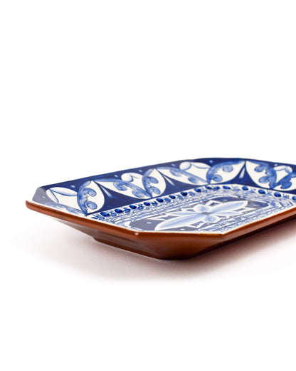 Decorative ceramic terracotta plate with blue and white pattern on a white background
