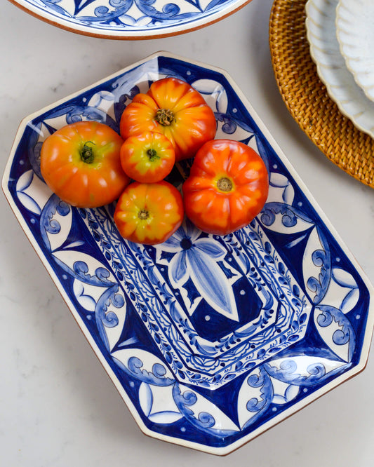 Decorative blue and white terracotta plate with orange tomatoes on a marble surface