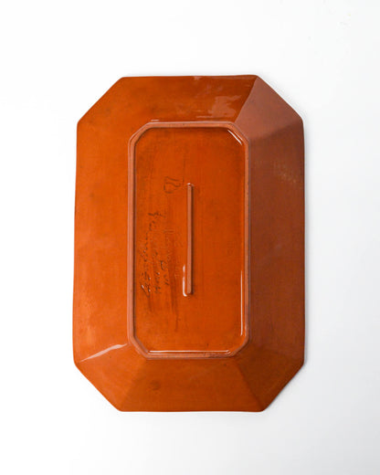 Detail of terracotta rectangular ceramic plate on a white background