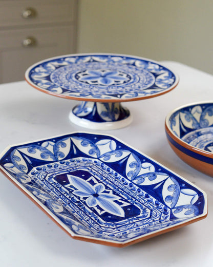 Set of blue and white ceramic terracotta dishes and a cake stand on a white marble surface