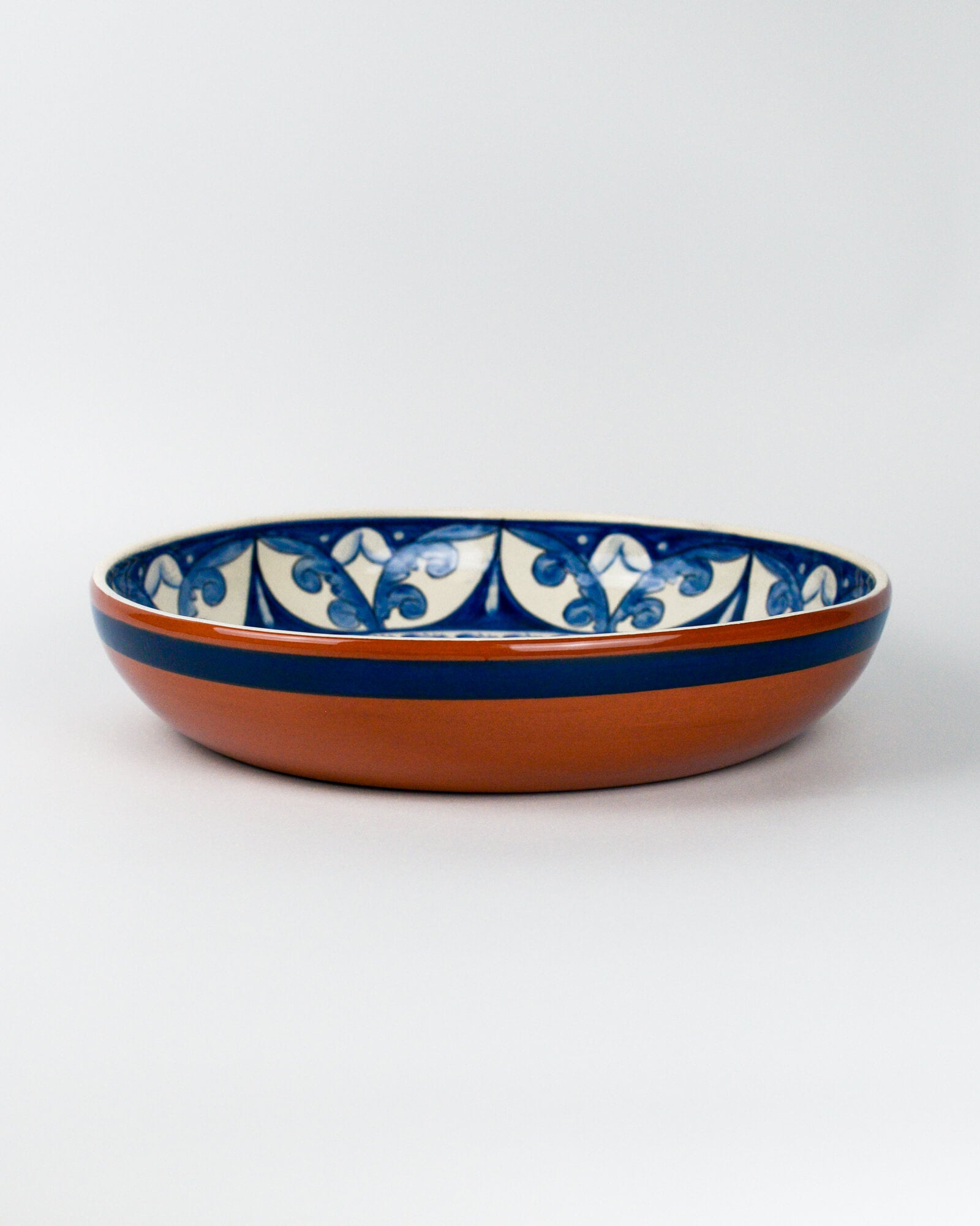 Ceramic terracotta bowl with blue and white floral patterns on a white background