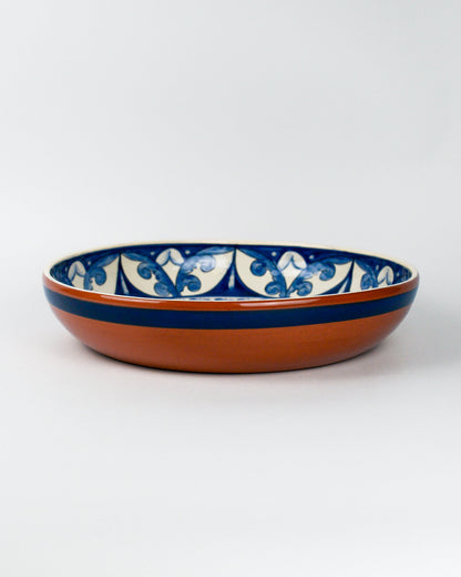 Ceramic terracotta bowl with blue and white floral patterns on a white background