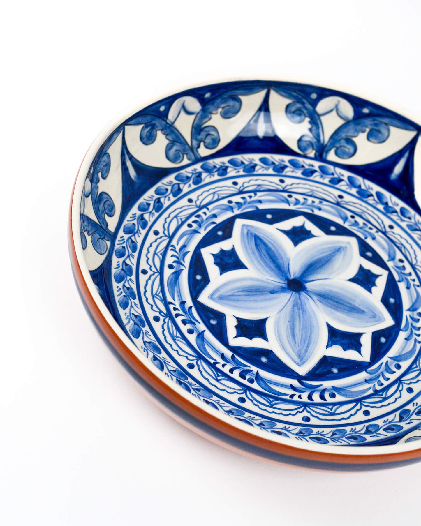 Ceramic terracotta serving bowl with blue and white floral design on a white background