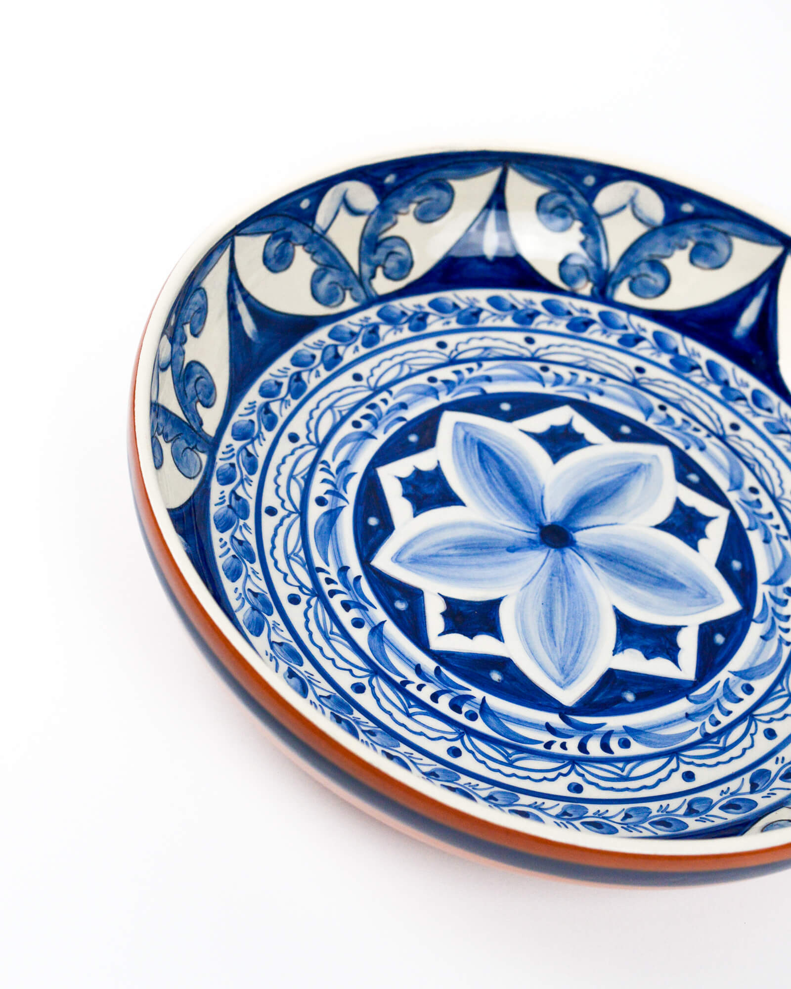 Ceramic terracotta serving bowl with blue and white floral design on a white background