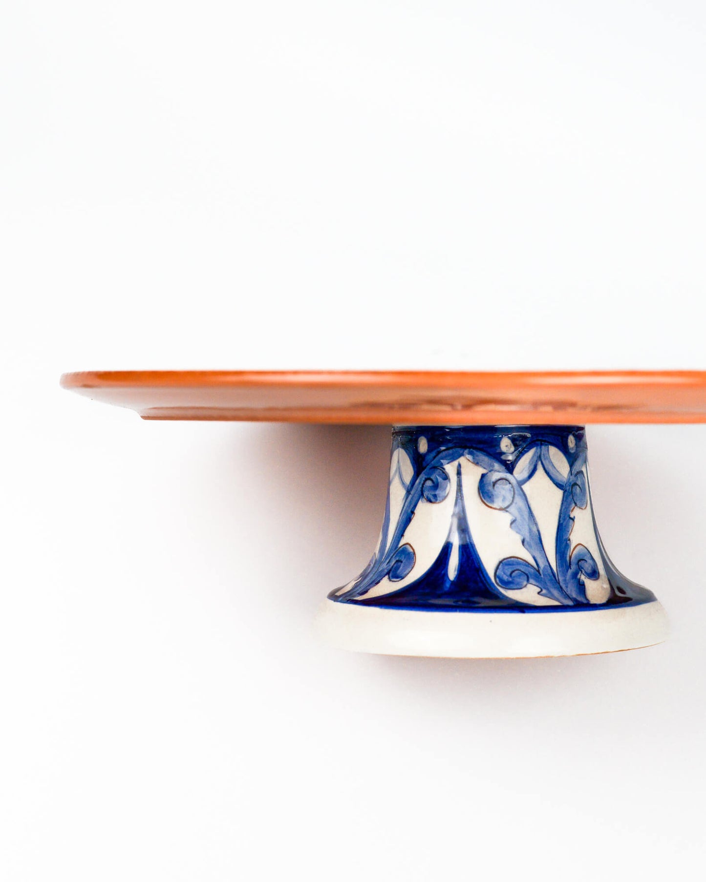 Ceramic terracotta cake stand with blue and white design on a white background