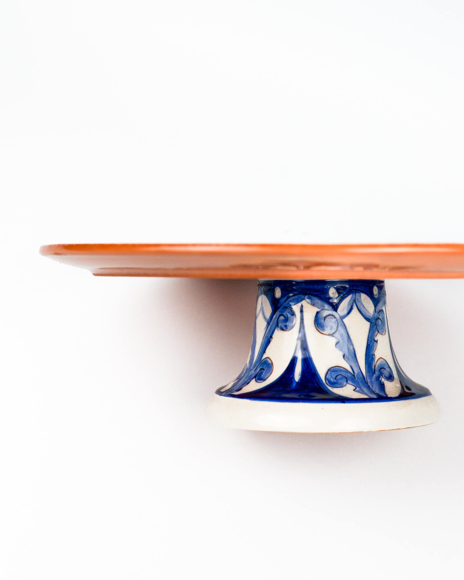 Ceramic terracotta cake stand with blue and white design on a white background