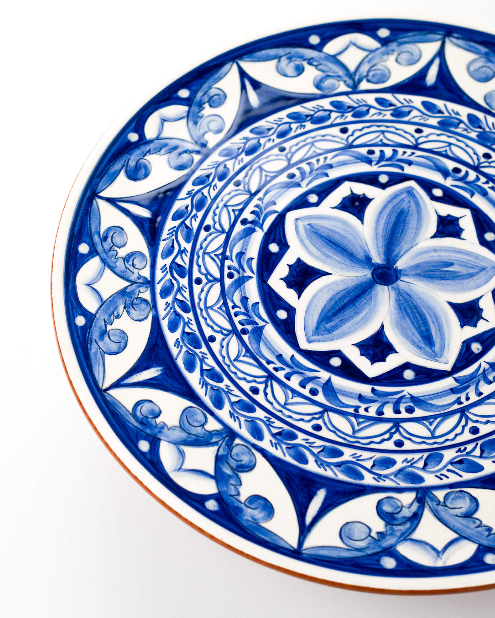 Decorative blue and white terracotta plate with intricate patterns on a white background