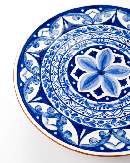 Decorative blue and white terracotta plate with intricate patterns on a white background