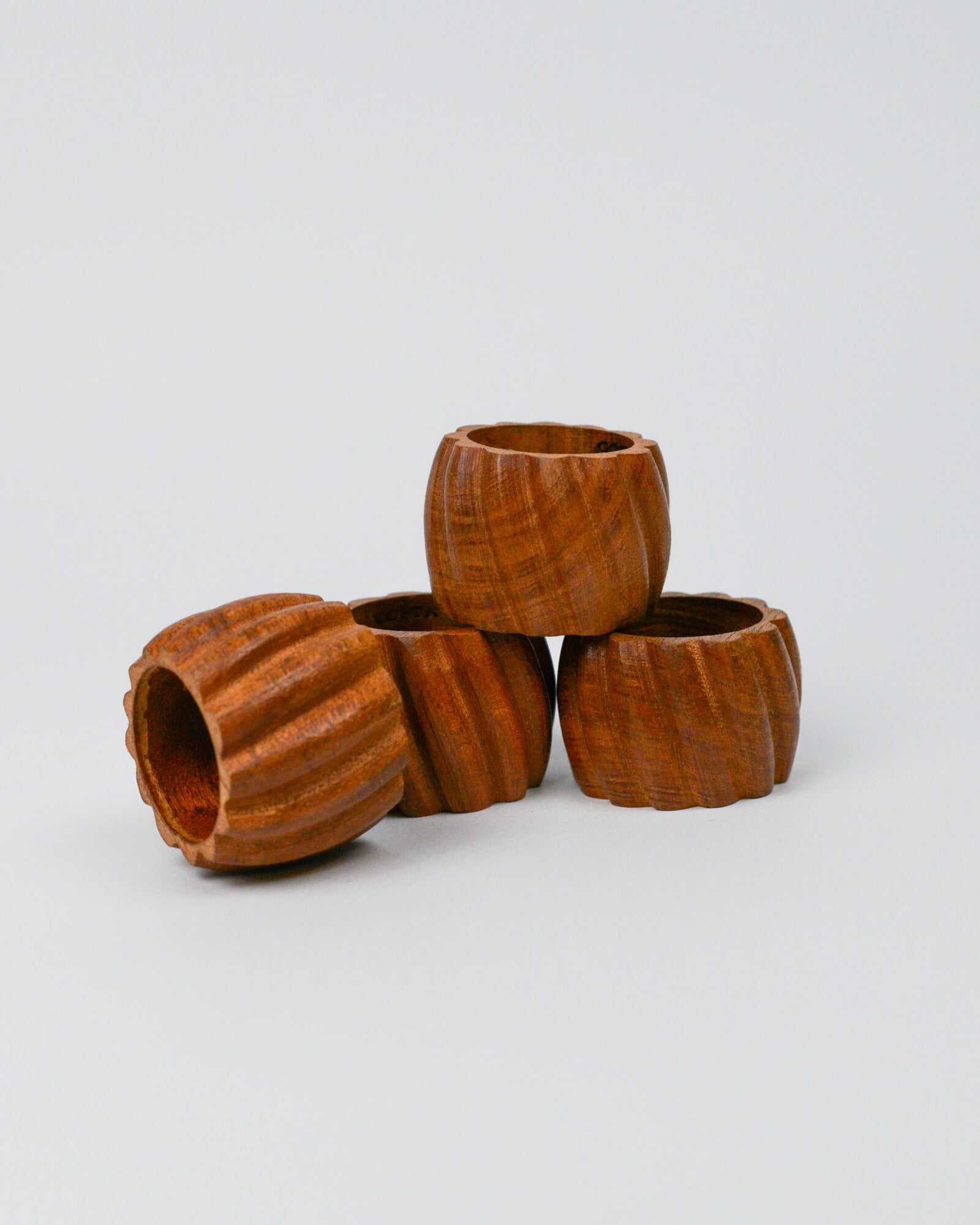 Stack of four wooden carved napkin rings on a white background