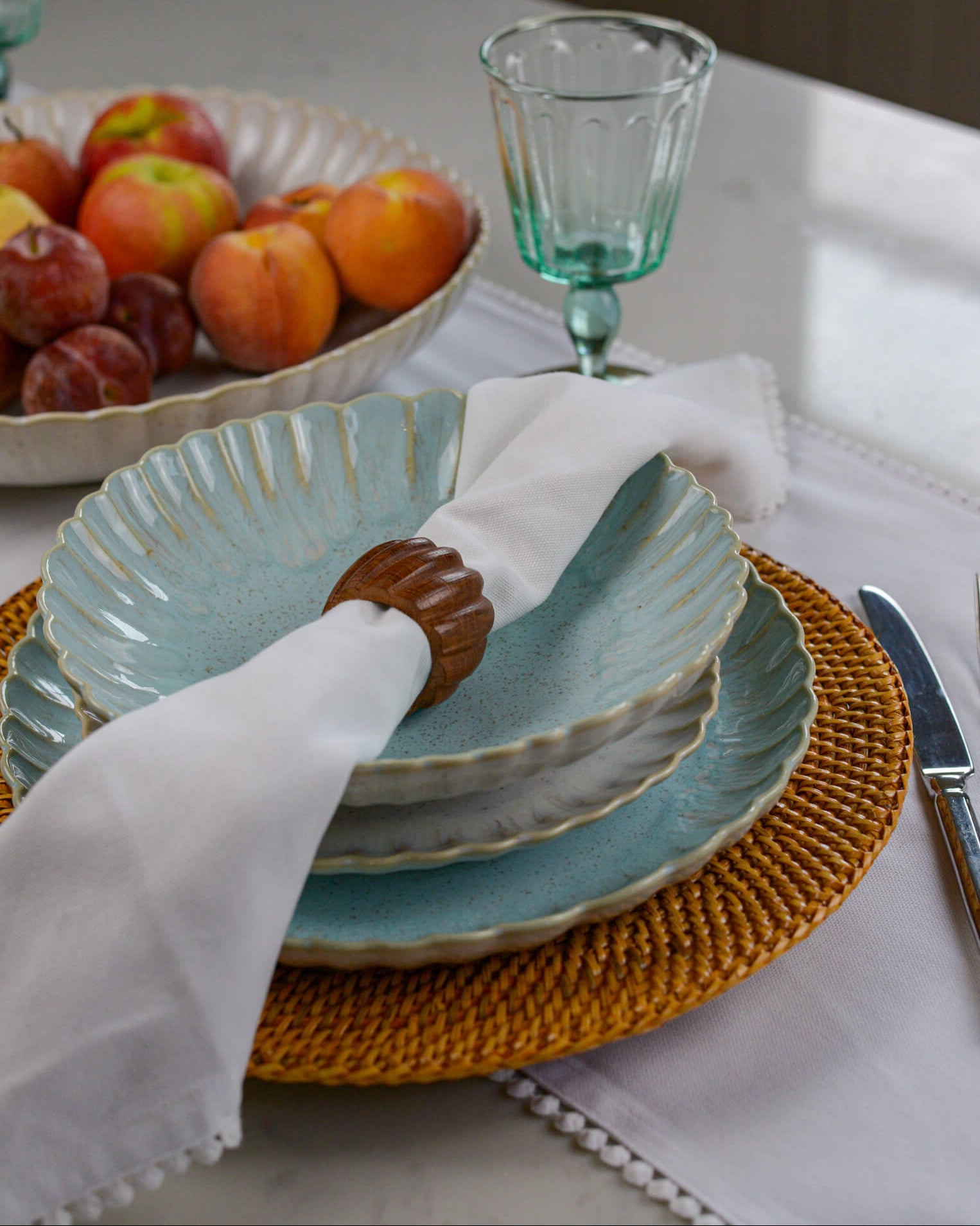 Dining table setting with blue plates, white napkin, and fruit bowl.