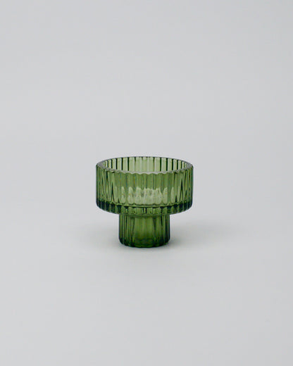 Green glass tealight candle holder on a white background
