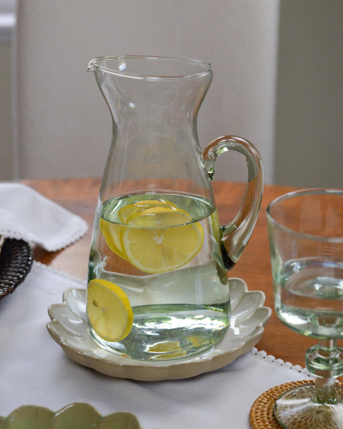 Clear glass pitcher with lemon slices on a wooden table