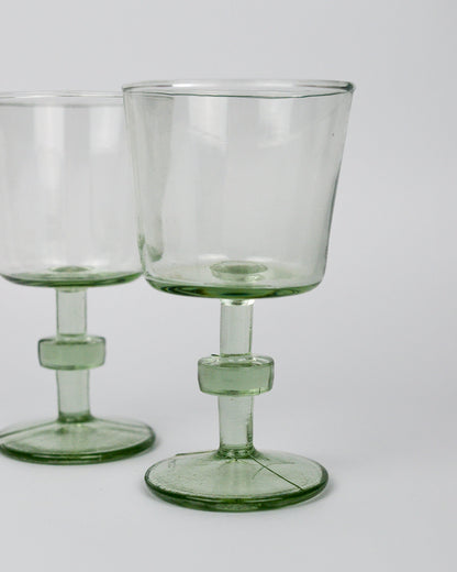 Two green glass goblet wineglasses on a white background