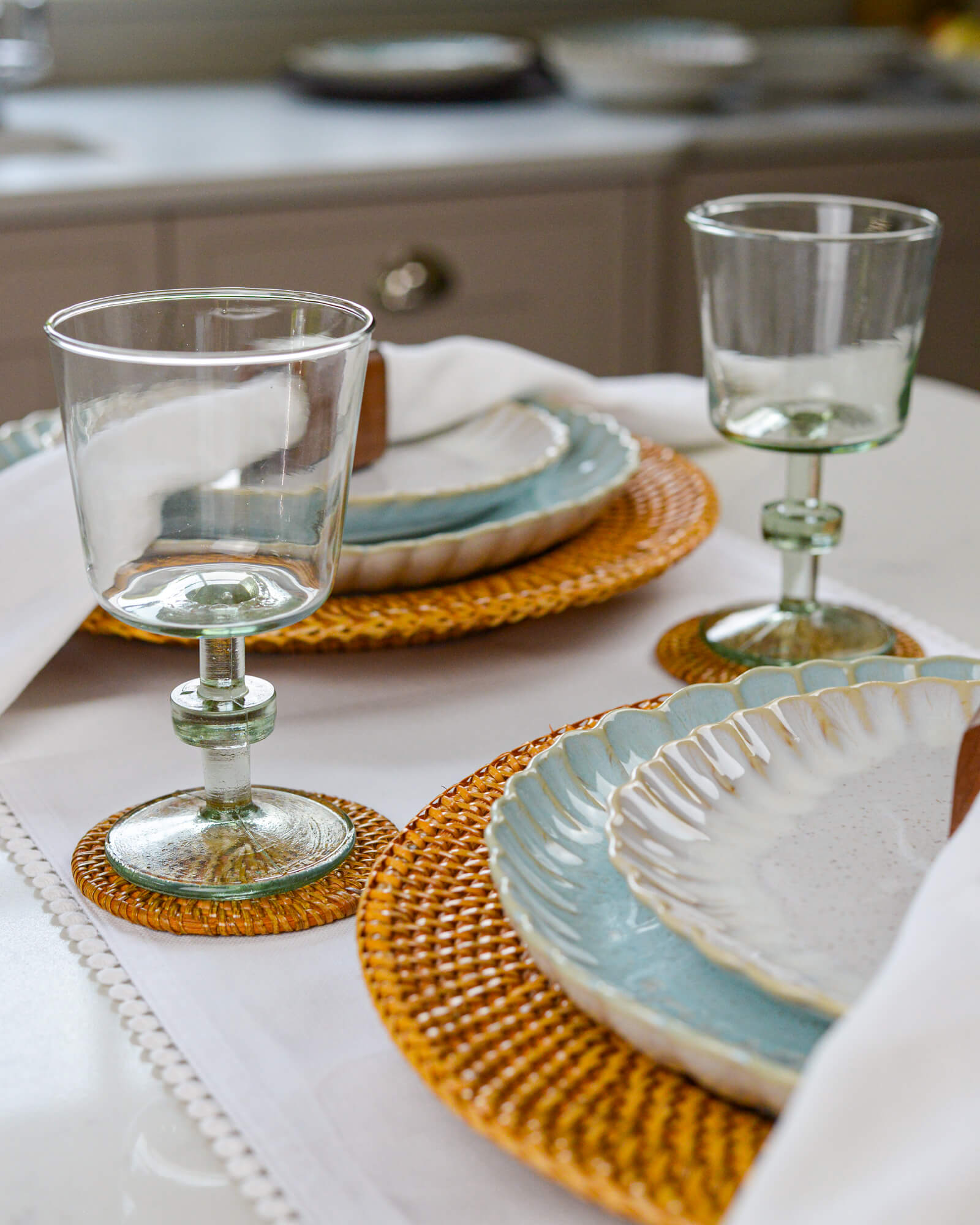 Table setting with glassware and ceramic plates on woven placemats.