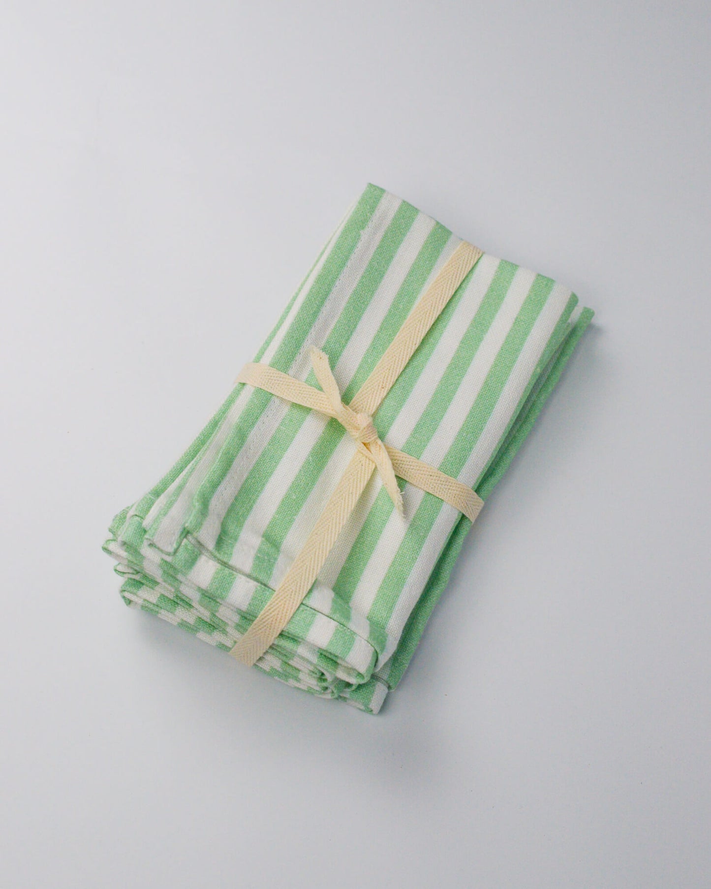 Green and white striped cloth cotton and linen blend napkin with a ribbon on a white background