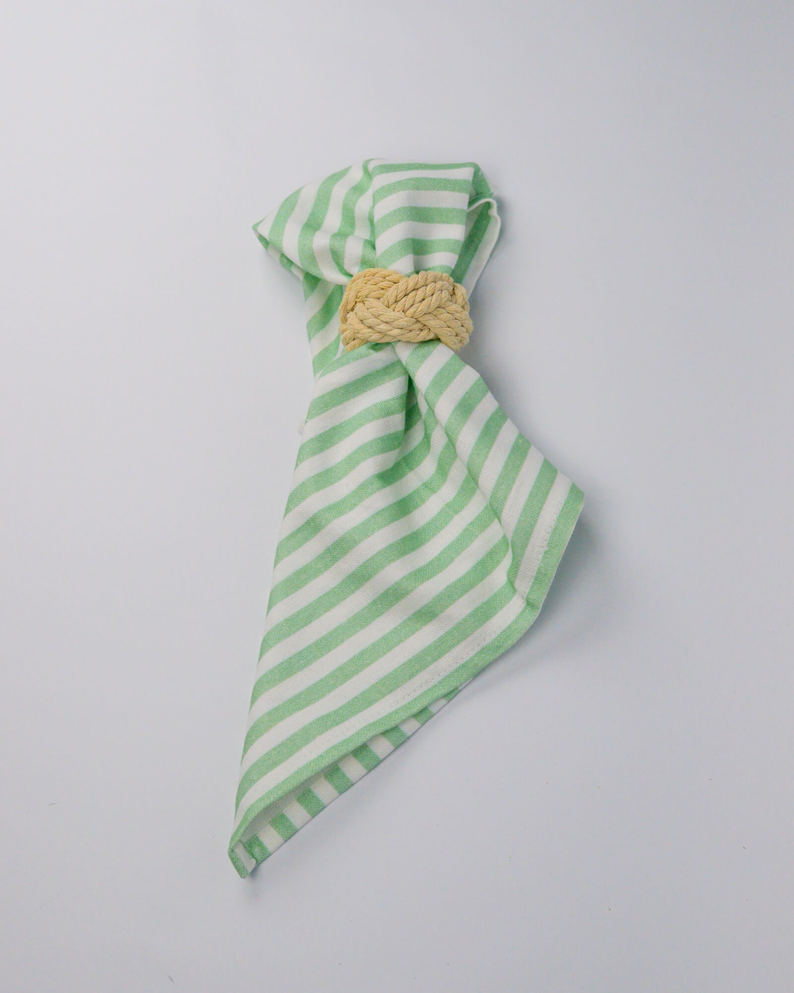 Green and white striped cotton and linen blend cloth napkin with a rope napkin ring on a white background