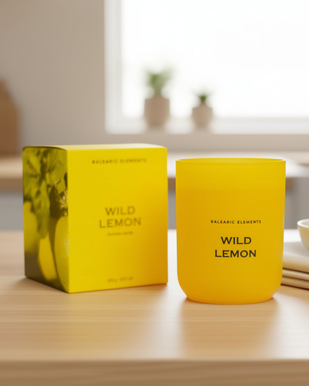 Yellow 'Wild Lemon' candle and packaging on a wooden surface with a blurred background